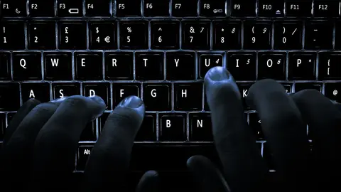 Kontoutskrift og sjetonger ved siden av en bærbar PC på et mørkt skrivebord