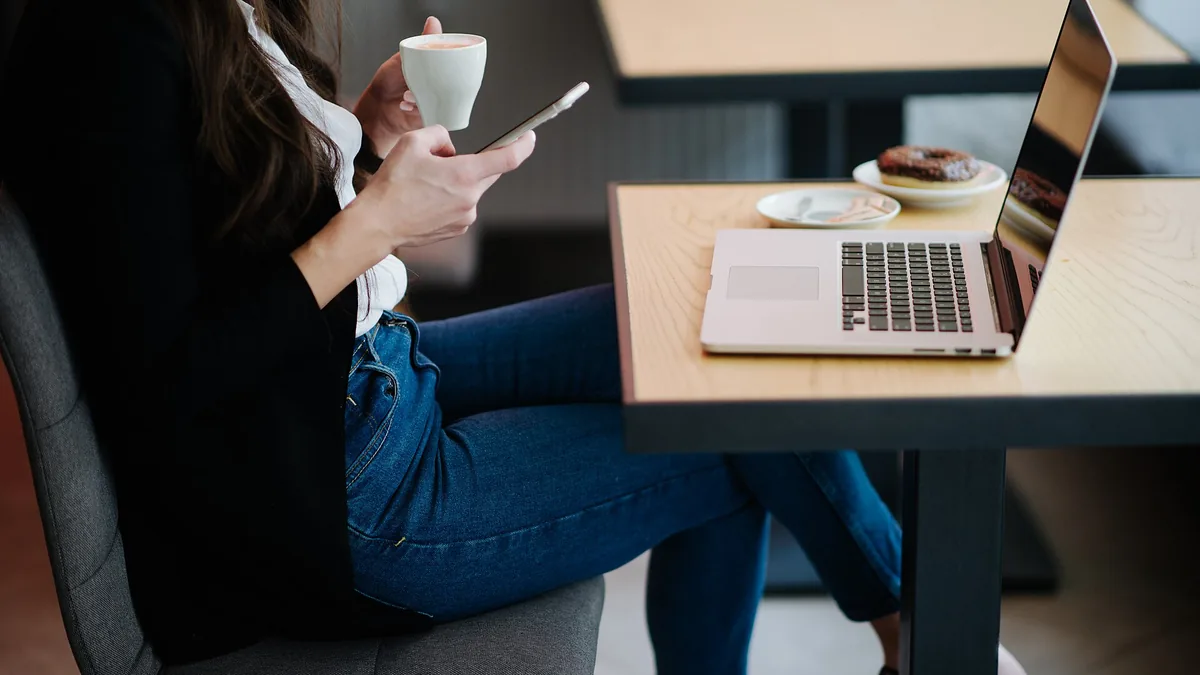Kaffekopp, mobiltelefon og sjetonger på et kafébord
